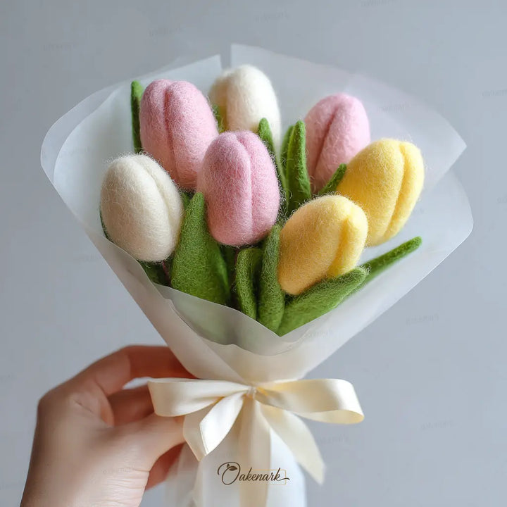 Bouquet of felt tulips in pink, yellow, and white held by a hand with a white background.