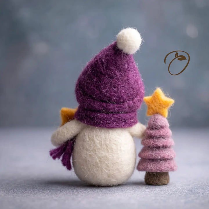 Back view of Starlight Snowman wool felt figurine with a purple pom-pom hat and scarf beside a star-topped tree