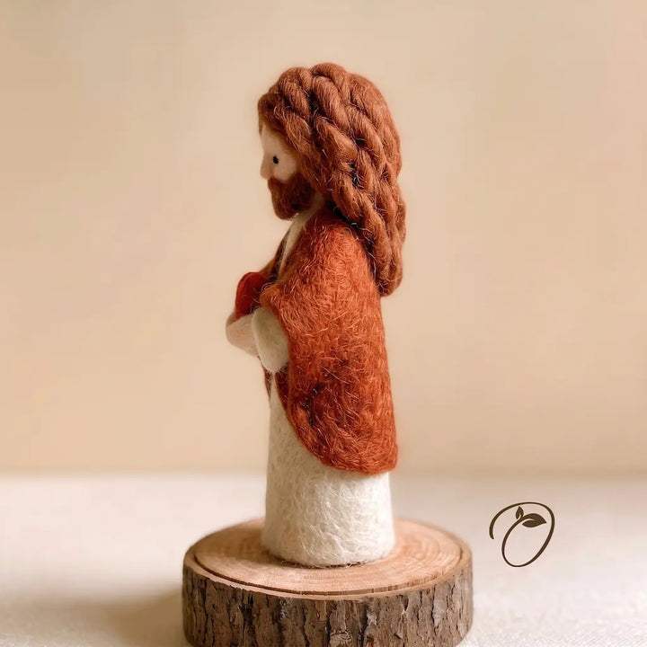 A handcrafted felted wool figurine of Jesus Christ shown in profile, standing on a rustic wood slice base against a soft beige background.